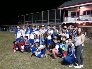 Equipo de futbol posando con un trofeo y medallas en la noche